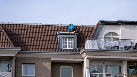 Mann klettert auf ein Hausdach