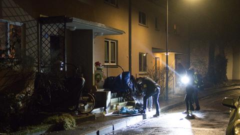 Polizistinnen und Polizisten untersuchen im Dunkeln einen Tatort in einer Wohnstraße.