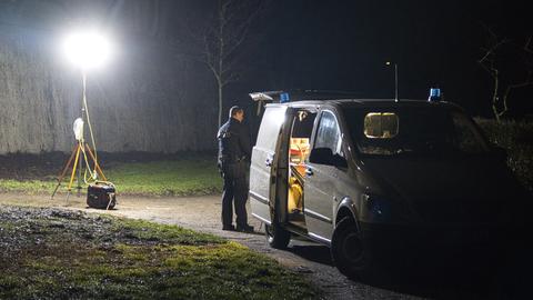 Ein Polizeiauto steht im Dunkeln in einer Kleingartenanlage.