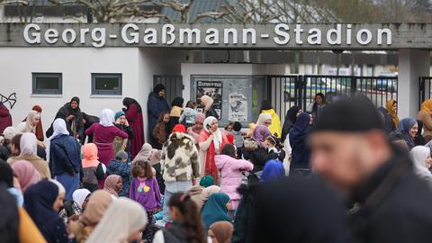 Eine Menschenmenge wartet vor dem Eingang eines Stadions.