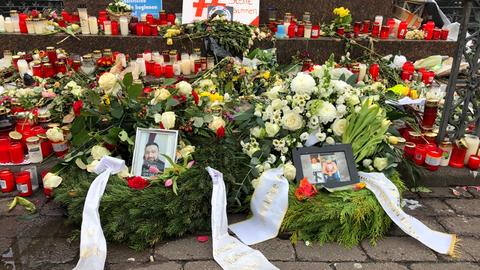 Blumen und Gestecke für die Opfer liegen auf dem Marktplatz in Hanau.