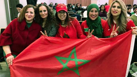 Fünf lachende Frauen, die eine Marokko-Flagge hochhalten.