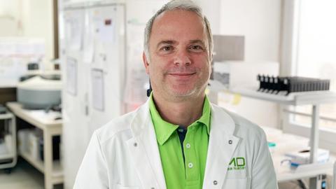 Der Virologe Martin Stürmer steht im Labor und lächelt in die Kamera.