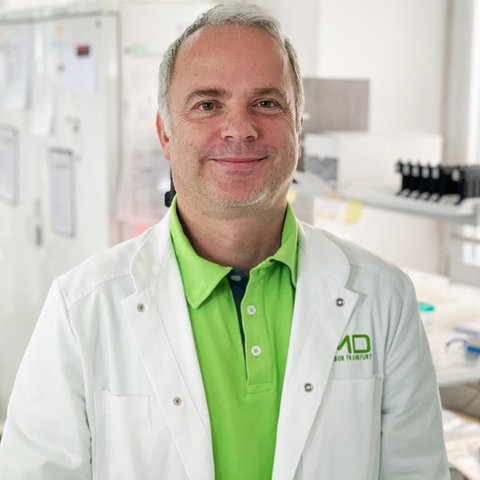 Der Virologe Martin Stürmer steht im Labor und lächelt in die Kamera.