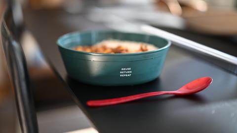 Eine Mehrwegschüssel steht mit Essen gefüllt auf einem Tisch. 