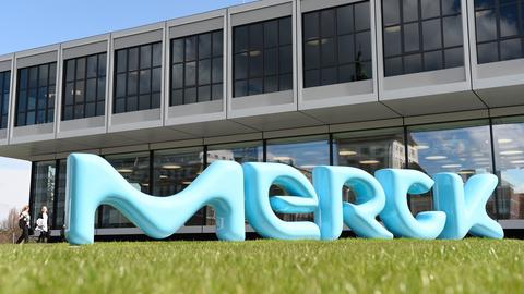 Das Gebäude von Merck, davor steht der Schriftzug in türkis auf einer Wiese.