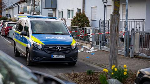 Ein Polizeiauto steht in einem Wohngebiet, daneben ist ein Tatort mit Absperrband gekennzeichnet.