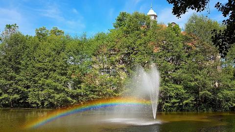 Ein Teich mit einem Springbrunnen, daneben ein kleiner Regenbogen
