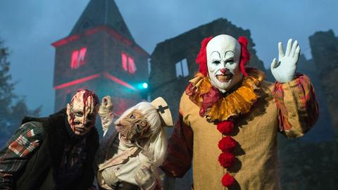 Ein missglücktes Opfer von Dr. Frankenstein (l-r), eine grausame Krankenschwester und der Clown "Pennywise" (Stephen Kings Roman "it") begrüßen vor der Kulisse der Burg Frankenstein in Mühltal am Samstagabend die Besucher.