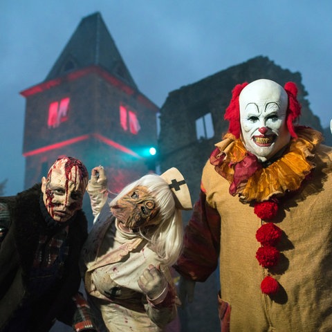 Ein missglücktes Opfer von Dr. Frankenstein (l-r), eine grausame Krankenschwester und der Clown "Pennywise" (Stephen Kings Roman "it") begrüßen vor der Kulisse der Burg Frankenstein in Mühltal am Samstagabend die Besucher.