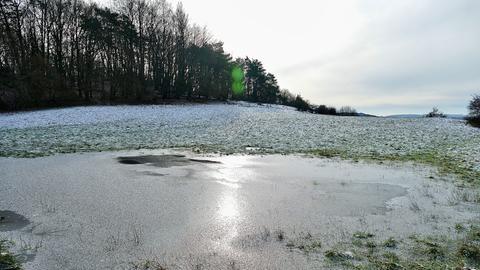 In einer ehemals mit Wasser gefüllten Wiesensenke hat sich ein kleiner Eissee gebildet.