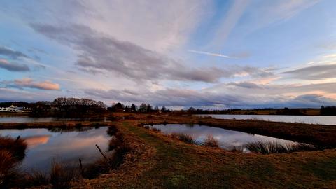 Rot-blauer Himmel über einem See und einer Wiese