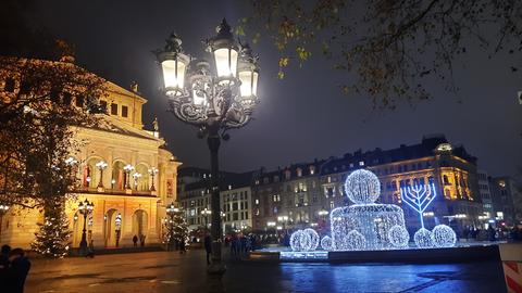 Opernplatz bei Nacht, weihnachtliche Beleuchtung am Brunnen davor sowie achtarmiger Chanukka-Leuchter als Lichtinstallation.