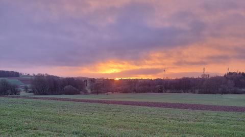 Ein Feld, dahinter geht die Sonne auf. 