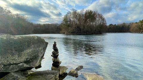 Steinanhäufung bei Sonnenschein vor einem See