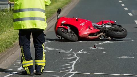 Motorrad liegt auf Straße, Mann mit Warnweste