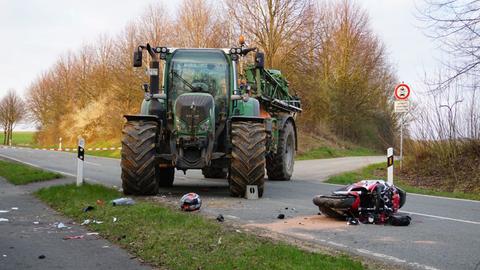 Ein beschädigtes Motorrad liegt nach einem Unfall vor einem Traktor auf einer Landstraße.