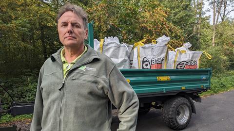 Jürgen Depenbrock vom Naturpark Habichtswald steht vor einem Anhänger mit großen Industrie-Müllsäcken.