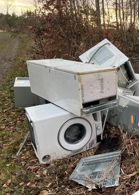 Übereinandergestapelt liegen alte Haushaltsgeräte an einem Feldweg. 