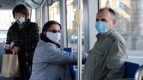 Menschen mit Mundschutz in einer Straßenbahn.