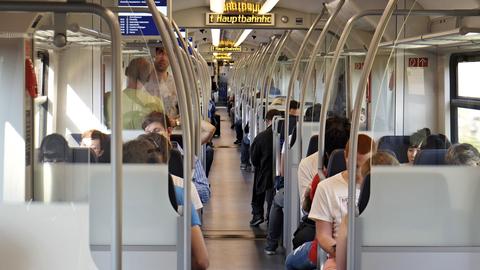 Zu sehen sind Menschen, in einem Abteil einer S-Bahn sitzend.