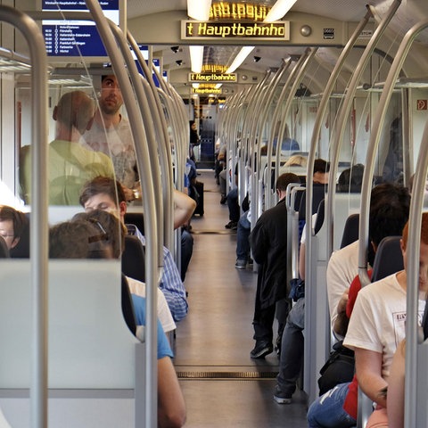 Zu sehen sind Menschen, in einem Abteil einer S-Bahn sitzend.