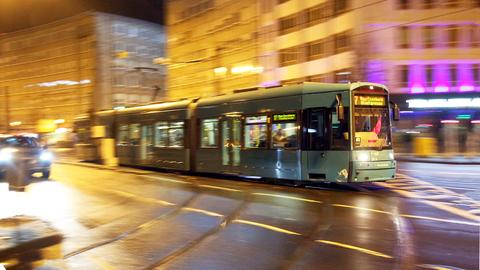 Zu sehen ist eine fahrende Straßenbahn im abendlichen Frankfurt.