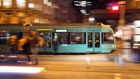 Das Foto zeigt eine fahrende Straßenbahn im nächtlichen Frankfurt.