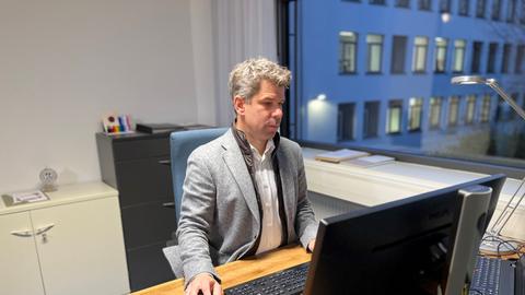 Der Universitäts-Präsident Thomas Nauss sitzt am Schreibtisch