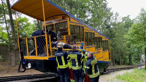 Feuerwehrleute tragen den Verletzten in die Bahn.