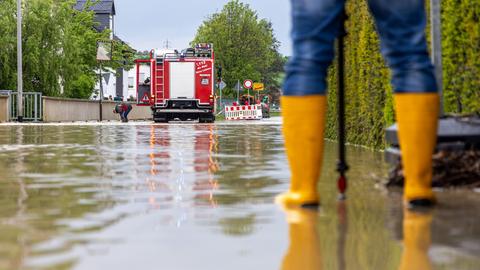 Feuerwehrleute arbeiten in einer überschwemmten Straße. 