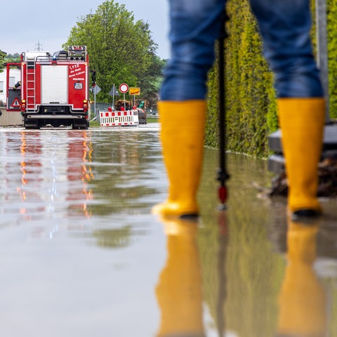 Feuerwehrleute arbeiten in einer überschwemmten Straße. 