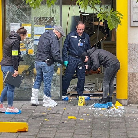 Beamte der Spurensicherung stehen am Eingang einer Bankfiliale