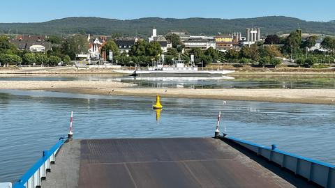 Im Bildvordergrund die Rampe eines Fährschiffes, das ein Flussufer ansteuert. Zwischen Rampe und Flussufer Wasser mit vielen deutlich sichtbaren Sandinseln (Sandbänken).