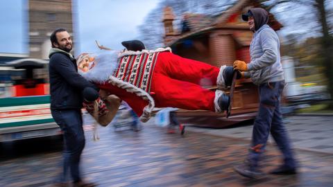 Mitarbeiter tragen einen Weihnachtsmann über die Straße.