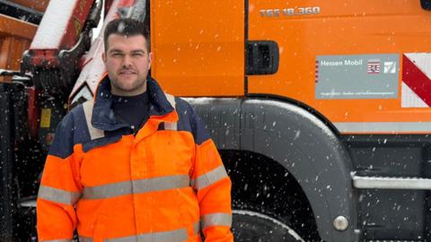 Straßenwärter Max Schützenmeister von HessenMobil steht vor seinem Räumfahrzeug im Schnee
