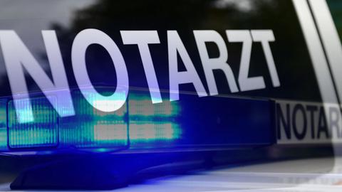 Auf der Scheibe eines Autos steht "Notarzt" und es spiegeln sich ein weiterer Schriftzug "Notarzt" und ein Blaulicht.