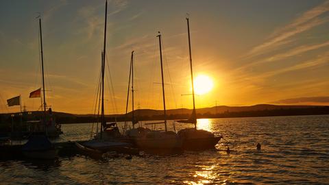 Am Singliser See stehen Boote an einem Hafen, die Sonne geht unter. 
