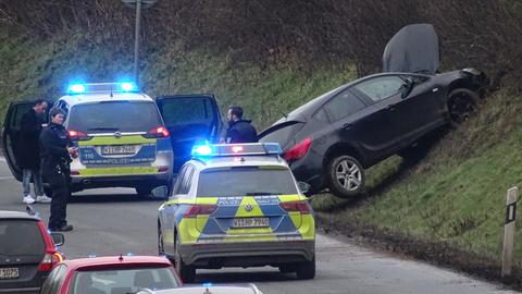 Schwarzes Auto an Unfallstelle mit Polizeiautos und Stau