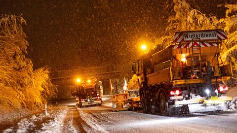 Fahrzeuge des Winterdienstes im Dunkeln mit Beleuchtung im Schnee