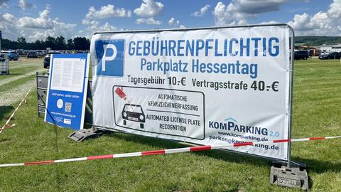 Ein Banner hängt an einem Metallzaun. Darauf steht: Gebührenpflichtig. Parkplatz Hessentag. Tagesgebühr: 10 Euro. Vertragsstrafe: 40 Euro.