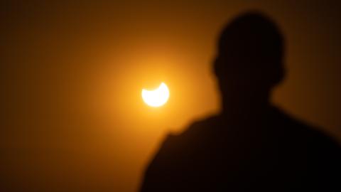 Eine Person beobachtet eine partielle Sonnenfinsternis. 