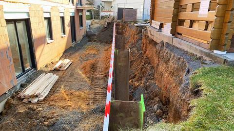 Baustelle mit Gartenhaus ... dazwischen Stahlstützpfähle und Absperrband