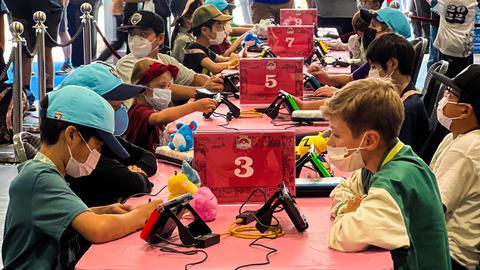 Kinder sitzen an Tischen im Wettkampf bei der Pokémon World Championship in London