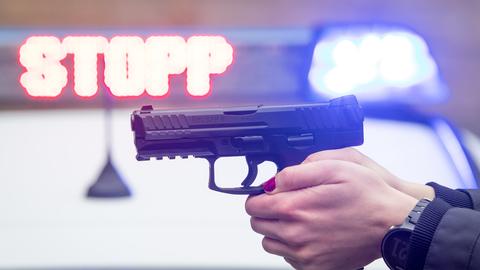 Polizei-Waffe im Anschlag. Im Hintergrund ist die LED-Anzeige "Stopp" zu lesen. 