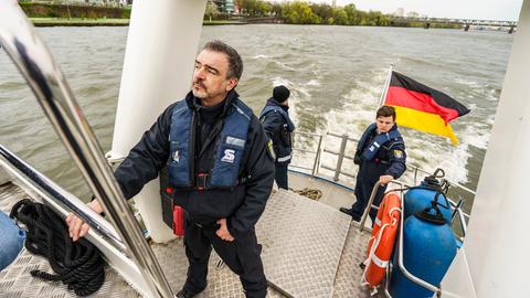 Harald Grund (l), Polizeioberkommissar von der Wasserschutzpolizei Frankfurt, steht mit Kollegen auf einem Boot der Wasserschutzpolizei.