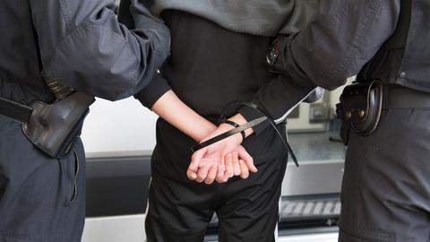 Eine mit Kabelbindern festgenommene Person wird abgeführt