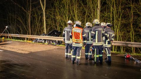 Eine Gruppe Menschen von der Feuerwehr Schlitz steht auf der Straße und schaut auf den Unfallwagen, der hinter der Leitplanke liegt.