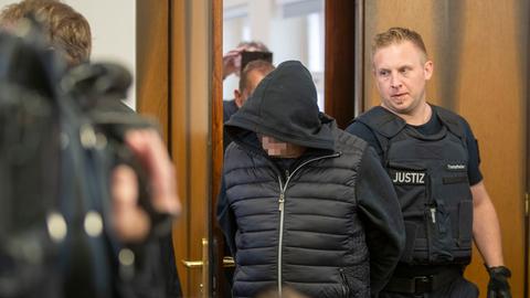 Der 62 Jahre alte Angeklagte (Mitte) wird in den Gerichtssaal in Darmstadt geführt.
