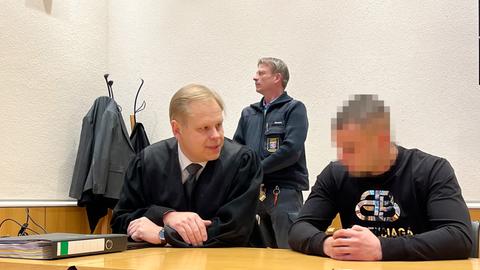 Ein Angeklagter (rechts) sitzt neben seinem Verteidiger und unterhält sich vor Prozessbeginn am Landgericht Fulda. 